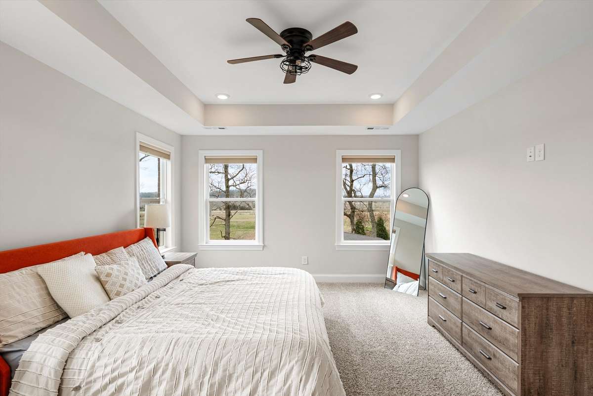 Spacious bedroom with tray ceiling, abundant natural light, and serene views—designed for comfort and everyday ease.