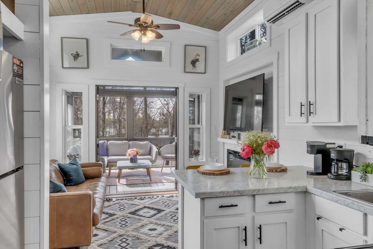 The sun-kissed living room has an electric fireplace, a ceiling fan and opens to the screened-in porch offering great flow for entertaining.