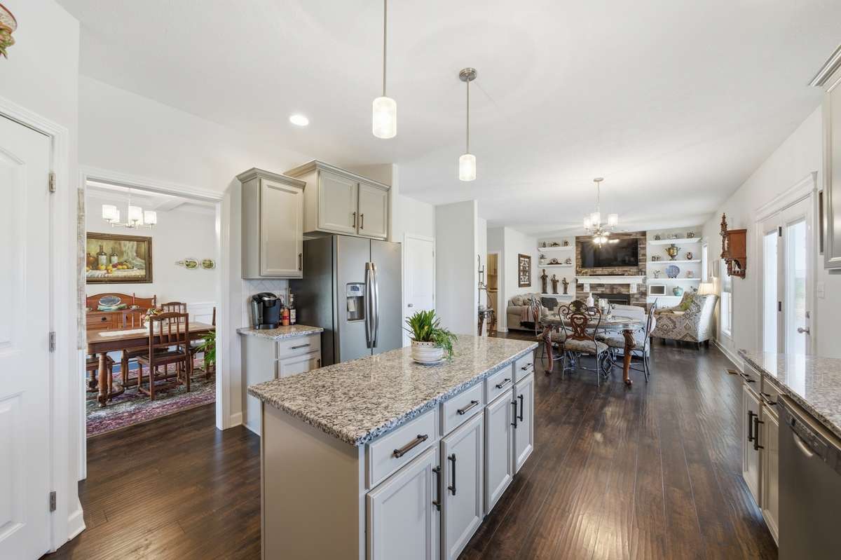 Spacious open-concept kitchen featuring granite countertops, large island, stainless steel appliances, and seamless flow into living and dining areas.