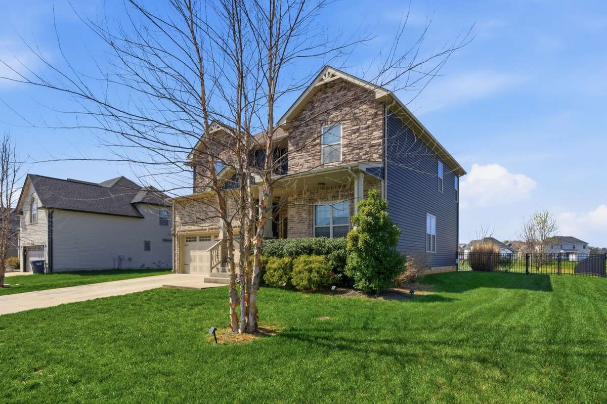 Front of house with beautiful landscaping and mature trees.