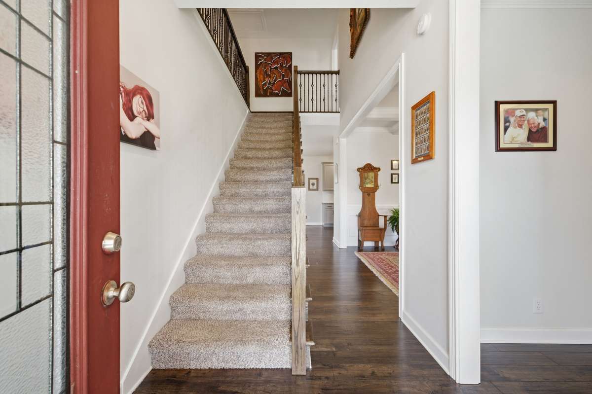 Welcoming foyer with hardwood floors, staircase entry, and open access to main living areas.