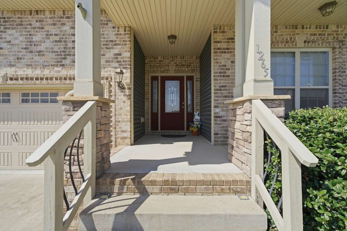 Inviting covered front porch with brick accents, columns, and welcoming entryway.
