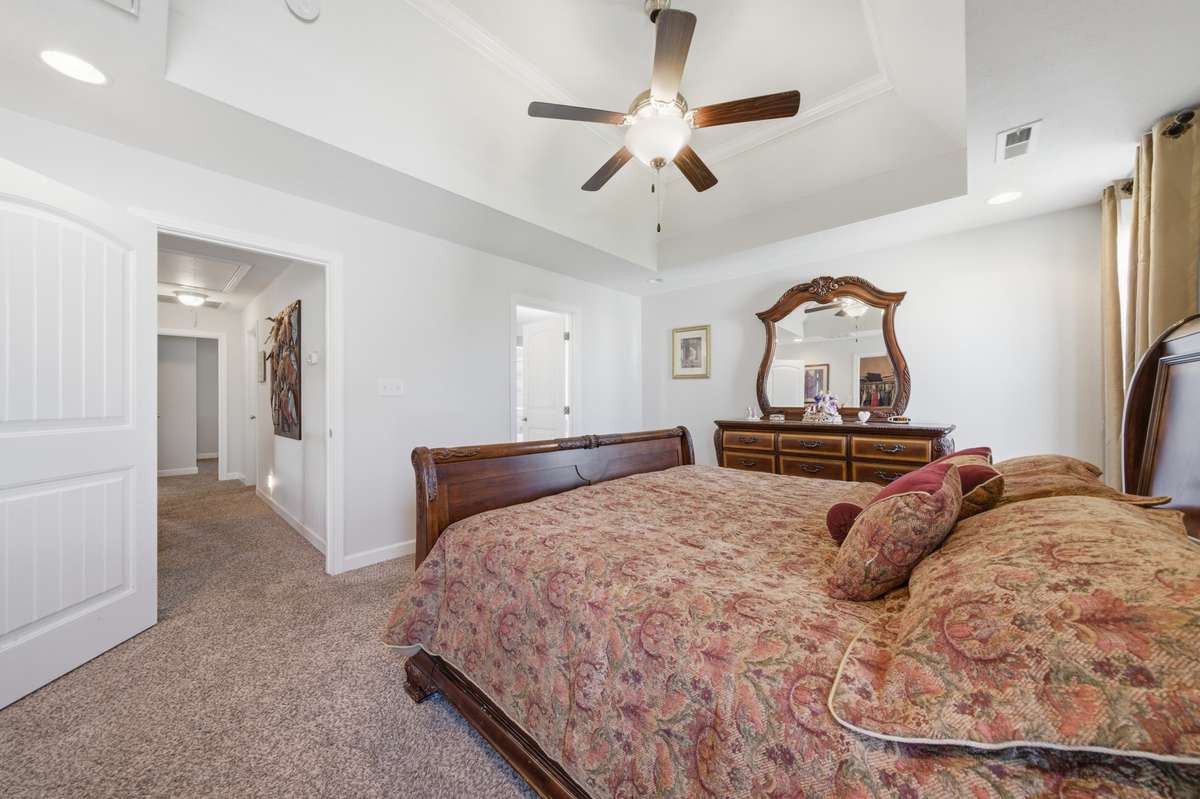 Spacious primary suite featuring a tray ceiling, ceiling fan, and ample natural light with a comfortable, open layout.
