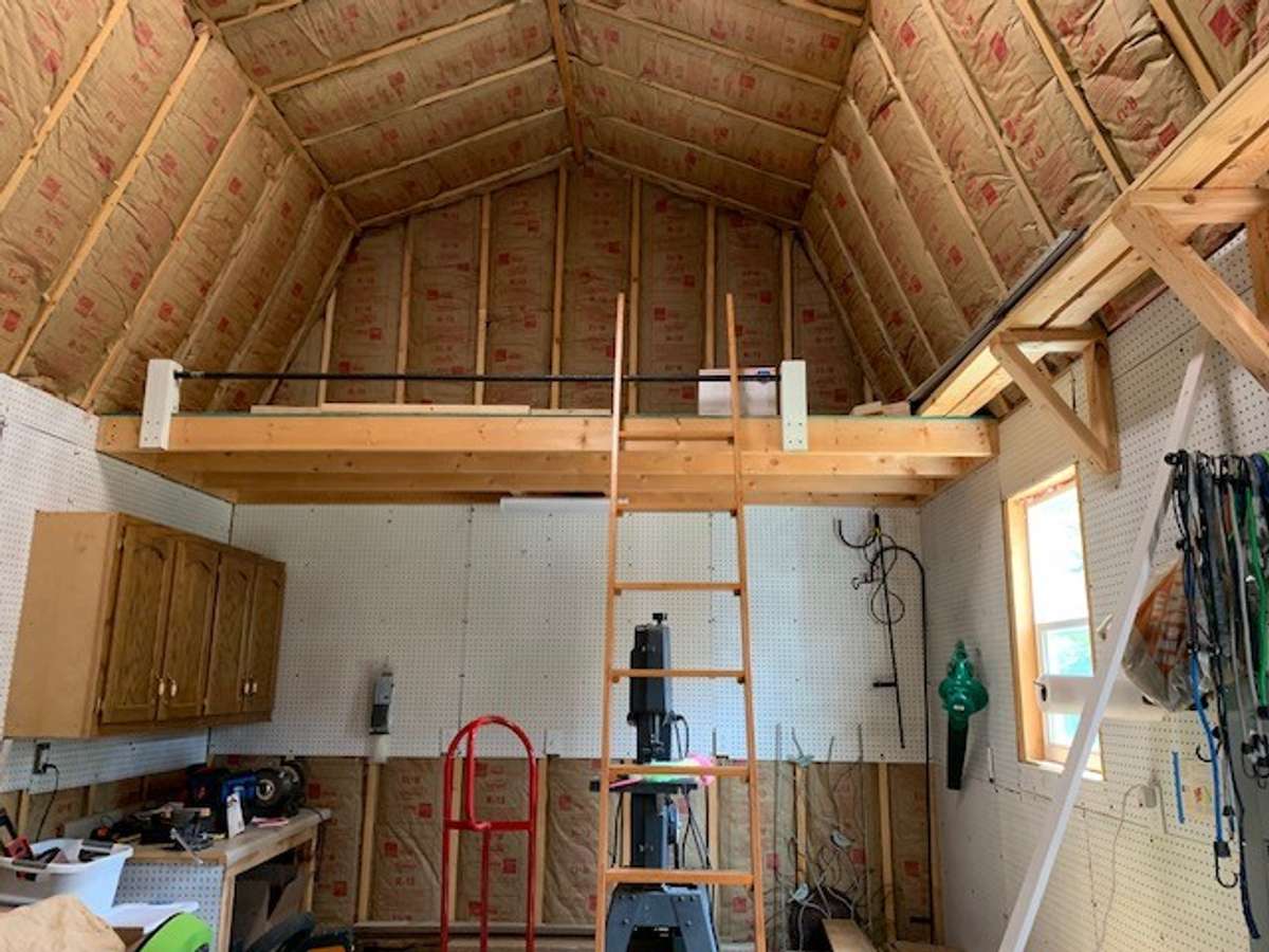 The storage building/workshop features abundant storage options, including shelving and open floor space for tools, equipment, and supplies.