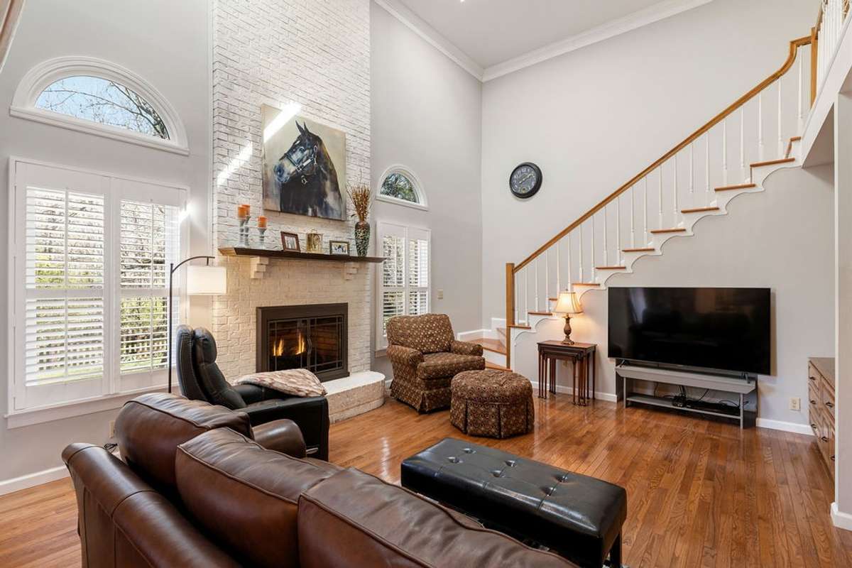 Fireplace with gas logs.  Large windows with palladian-style windows above.  Staircase leading upstairs.