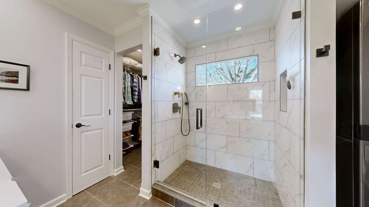 Beautifully renovated primary bathroom featuring a lovely tiled shower with frameless glass door and product niche.