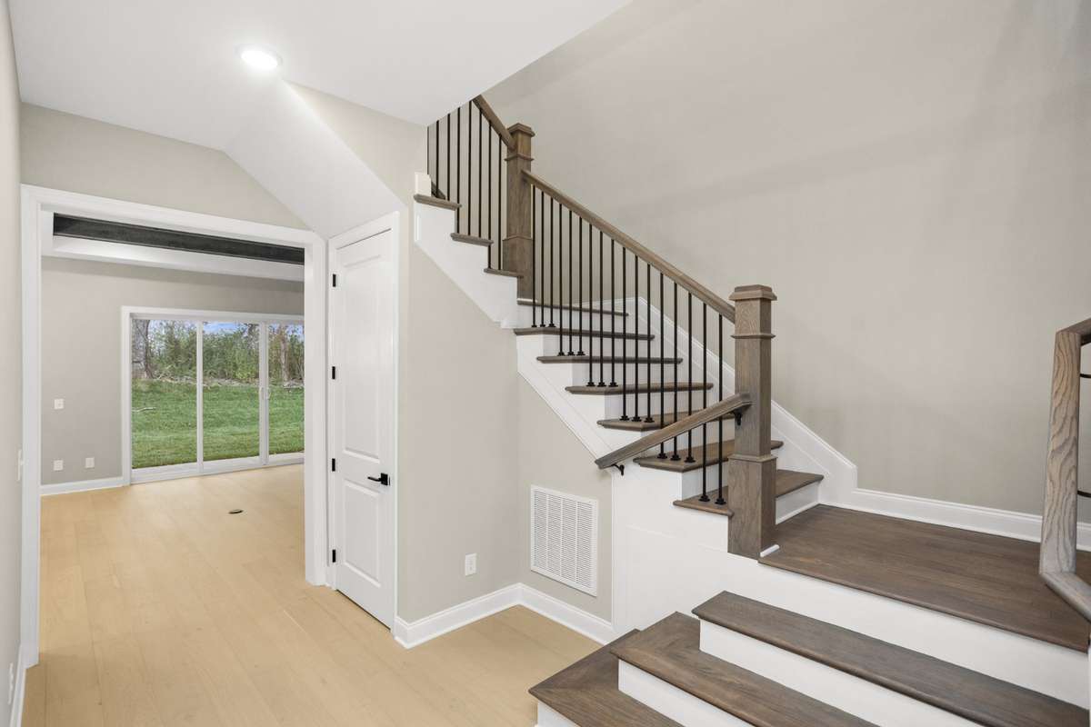 Hallway and then the staircase to the 2nd floor, with a view into the family room, with a view of the back yard