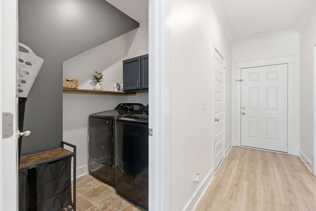 The functional laundry space offers both style and practicality with built-in shelving and additional storage. Tucked neatly away yet easily accessible, it provides the perfect spot for everyday tasks while maintaining a clean, organized feel.