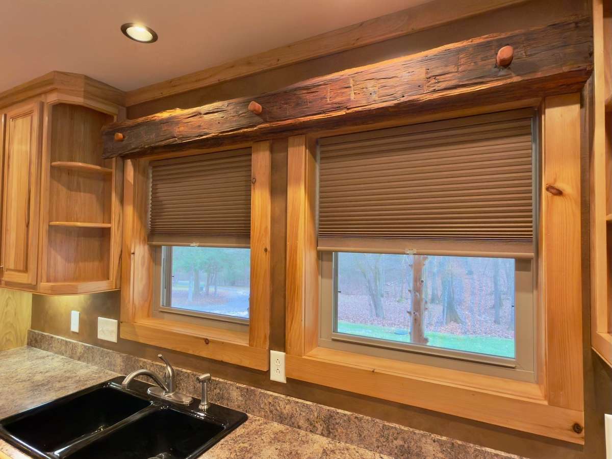 Hand hewn log frame over kitchen windows that overlook the front yard.