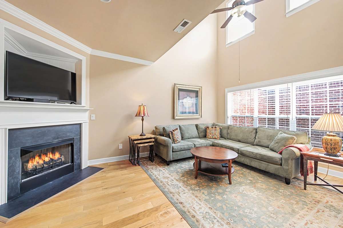 Bright and inviting living room featuring soaring vaulted ceilings and abundant natural light. The cozy fireplace with gas insert creates a warm focal point.