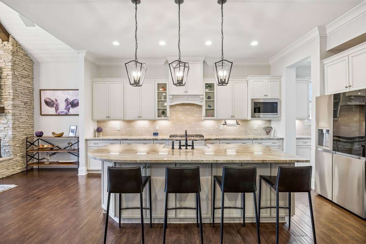 Elegant Kitchen with quartz counters, tile backsplash and stainless steel appliances that include double ovens.