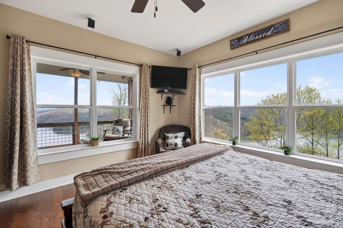 Lake views from both windows of primary bedroom and doorway leading out to covered porch