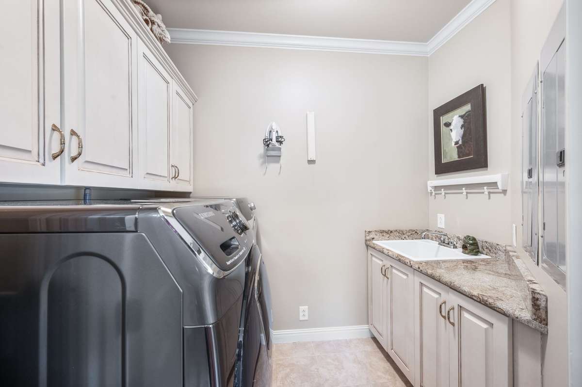 separate laundry room with utility sink and custom cabinetry.