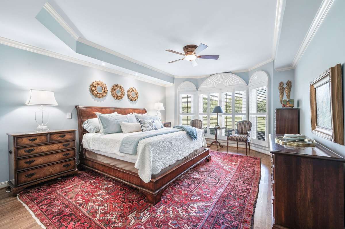 Primary Bedroom, with fresh new custom color paint, new hardwood floors, plantation shutters, tray ceilings. new ceiling fan.