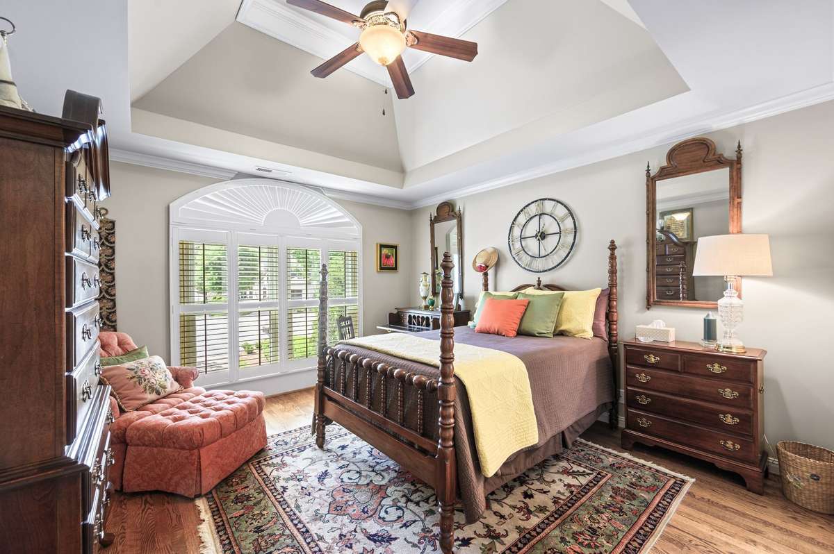 vaulted and tray ceiling in bedroom upstairs with hardwoods and plantation shutters