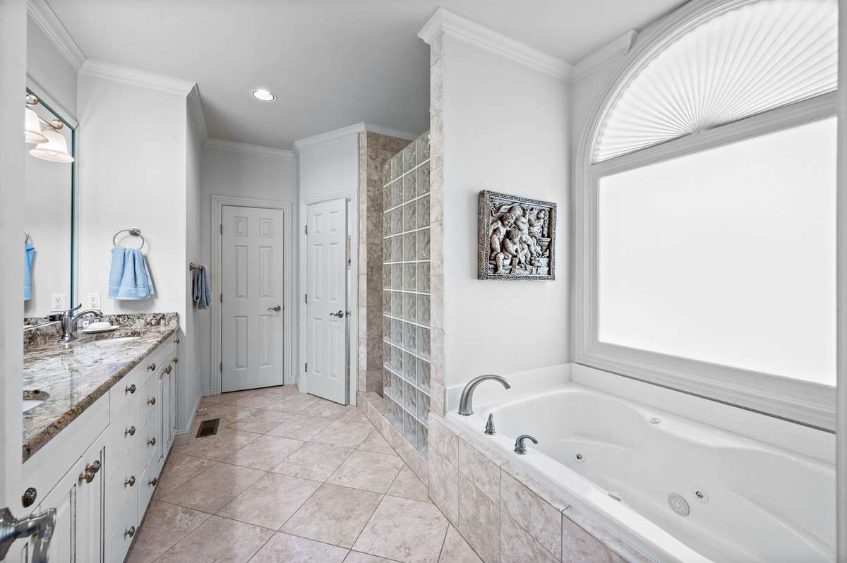 primary suite full bath with separate jetted tub and walk-in tiled shower. custom built-ins.