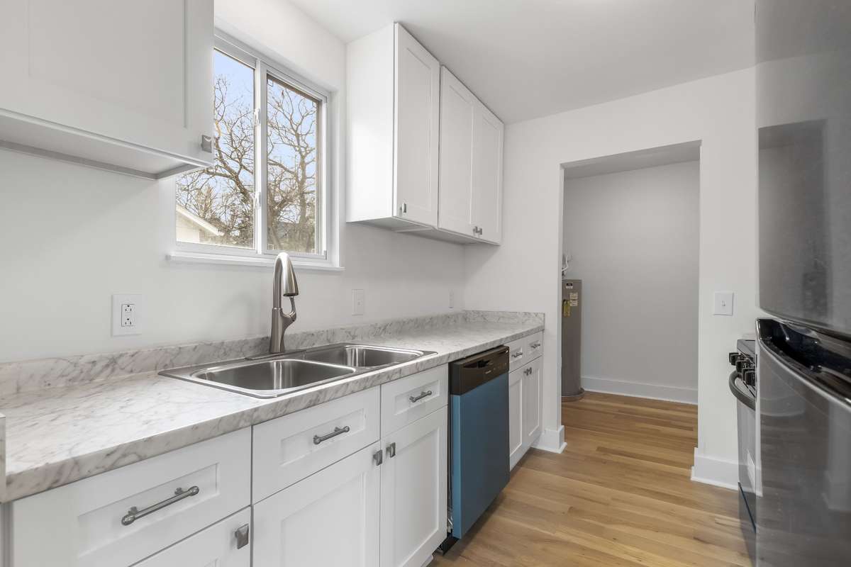 The updated kitchen features white cabinetry, stainless steel appliances, and a clean, modern feel.