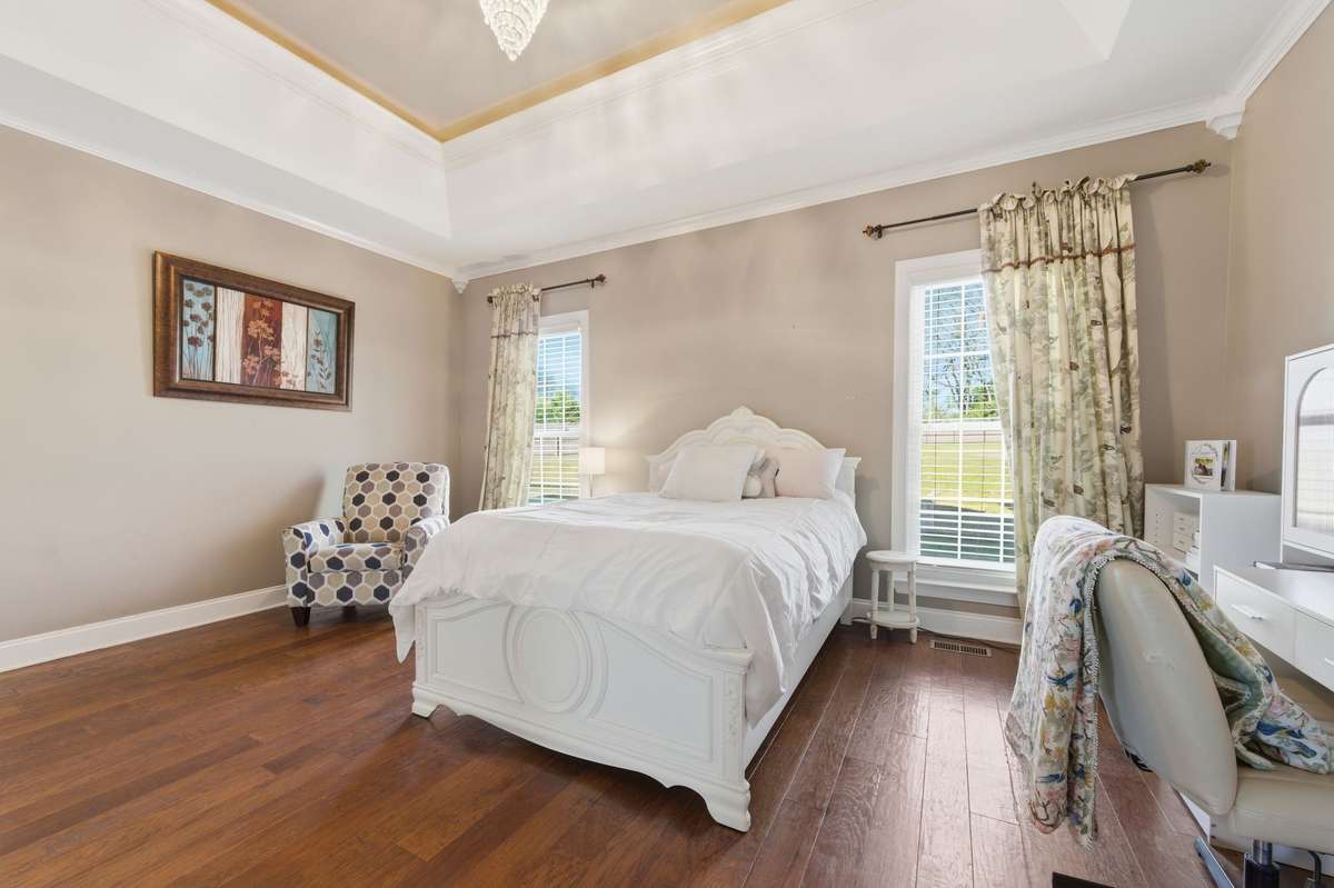 This spacious primary bedroom offers a relaxing retreat, featuring a tray ceiling, walk-in closet, and a private en suite bathroom.