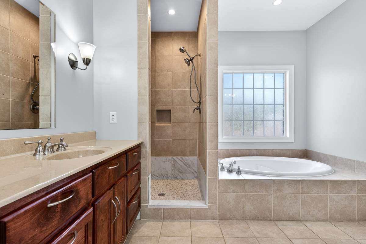 Primary bathroom with walk-in shower, double vanities, and garden tub