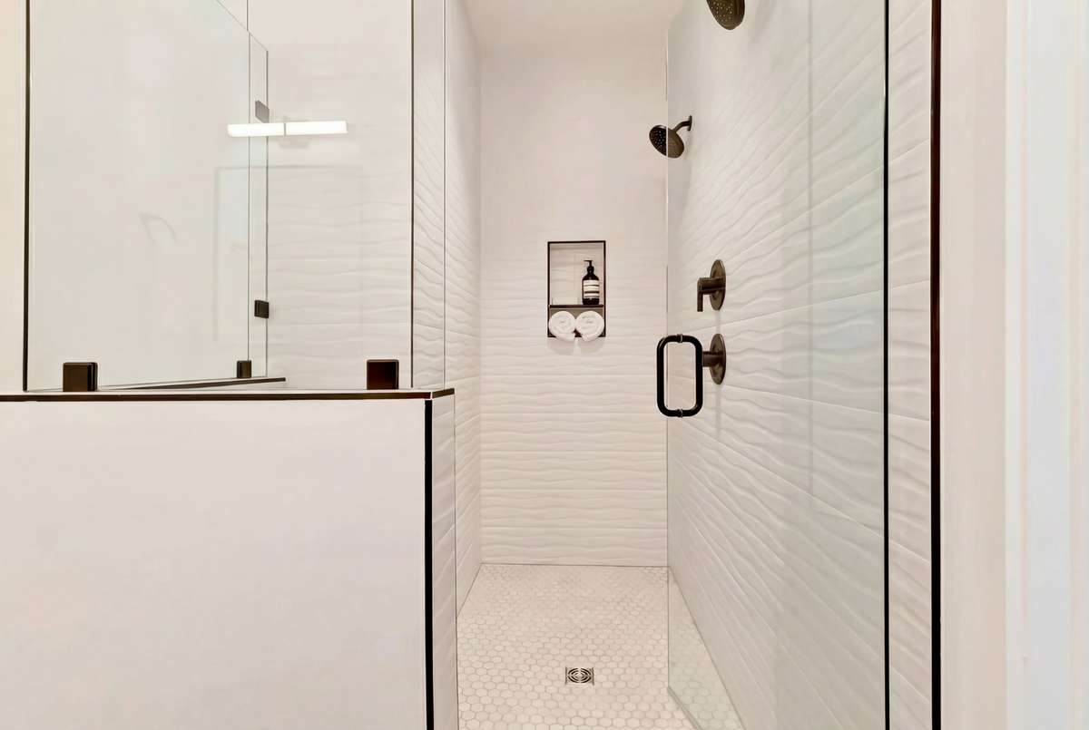 The custom walk-in shower features dual showerheads and timeless white tile.