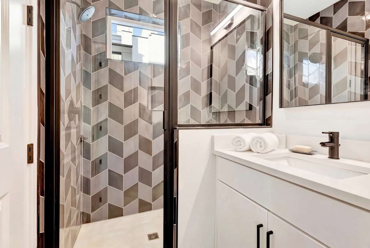 The custom tile work makes each bathroom feel unique, but they share the same convenient features: quartz counters, modern lights and mirrors, and extra vanity storage!