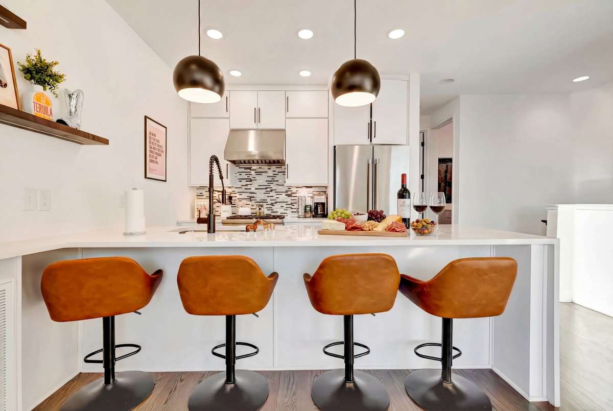 Elegant pendant lights illuminate the big quartz breakfast bar.