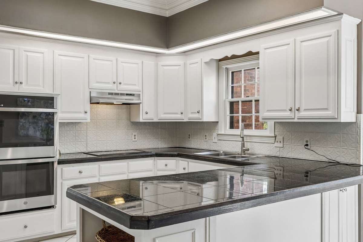 The stainless appliances include a double oven, electric cooktop, dishwasher, and refrigerator that conveys with the home.