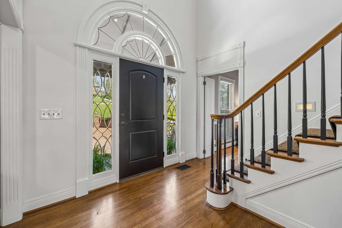 The staircase features a striking wood banister with decorative iron spindles.