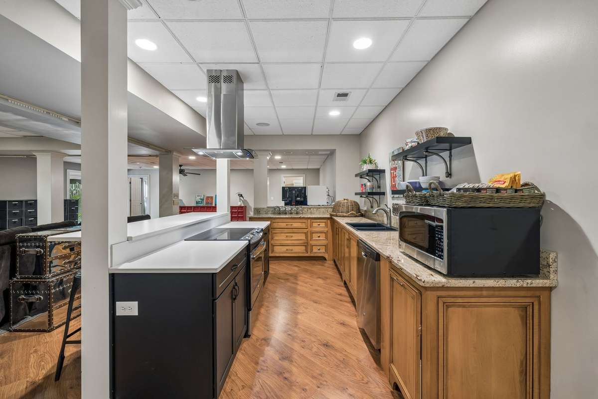 The lower level boasts a full kitchen with a built in stove and cooktop, a sink, space for a refrigerator, plenty of cabinetry and countertop space and decorative floating shelving.