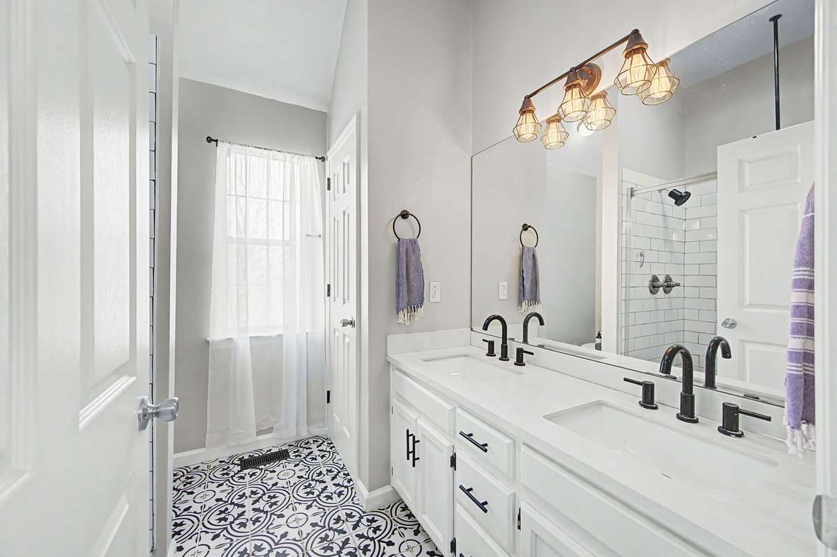 Renovated primary bath has darling mosaic floor and double vanities with quartz counters.