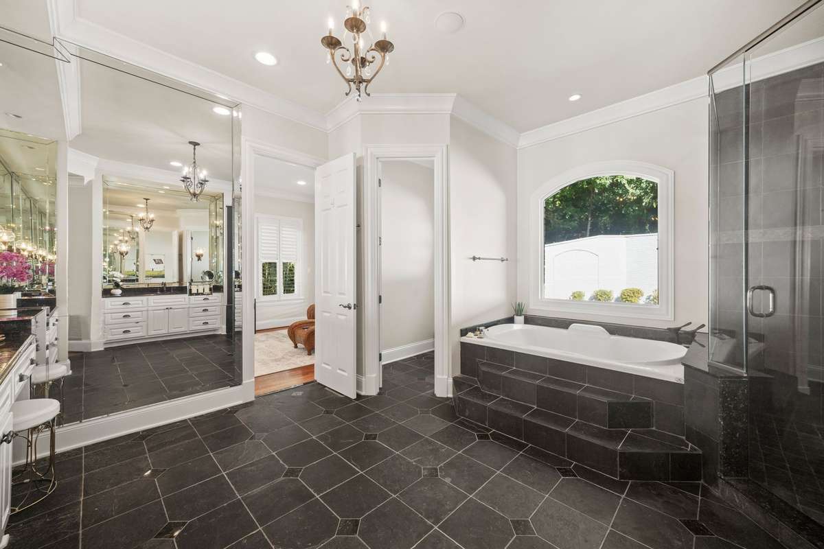 Elegant ensuite bath with double vanities, mirrored wall, spa tub, slate tile shower.