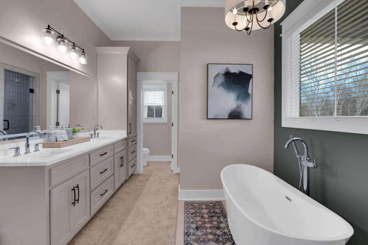 Primary bath with a walk in tile shower with double rain heads and seat, a soaking tub and double vanities with a lighted mirror