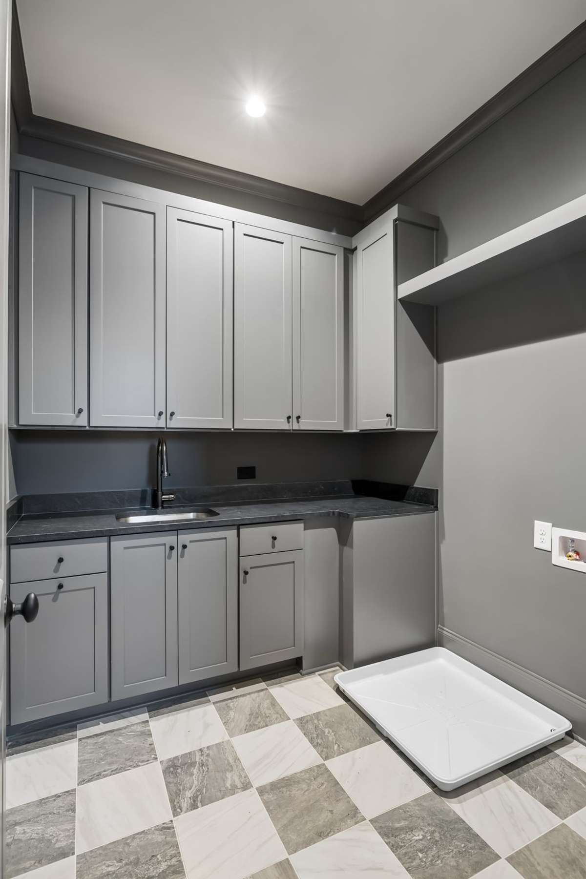 Well-appointed laundry room featuring custom cabinetry, a utility sink, and generous counter space for folding and organization. Designed with both style and function in mind, this space offers ample storage and makes laundry days better