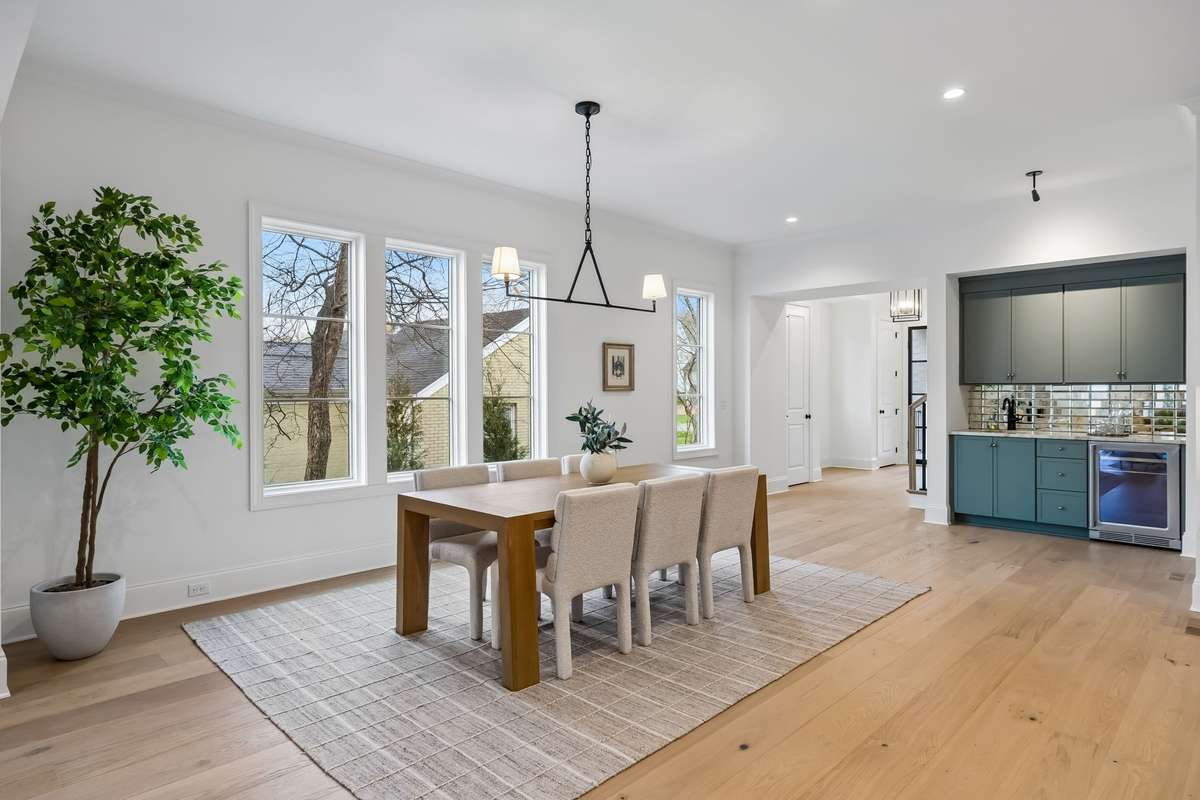 The large dining area flows naturally into the naturally into the heart of the home, where warm wood cabinetry, light-filled interiors, and clean, modern finishes create a welcoming atmosphere.