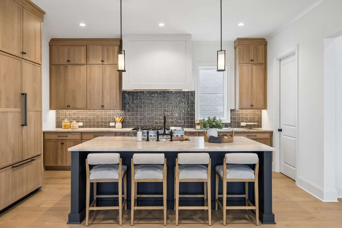 Designer kitchen with a perfect blend of warmth and sophistication. Custom white oak cabinetry, a statement island with seating for four, and a full-height tile backsplash create a clean, elevated look. Thoughtfully designed with abundant storage