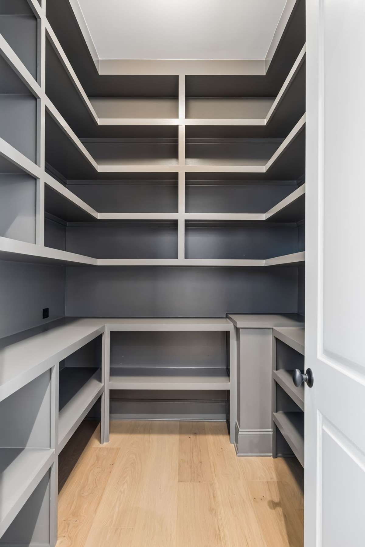 Spacious walk-in pantry with custom built-in shelving and abundant storage, designed to keep everything organized and easily accessible. This thoughtful layout with prep counter space adds functionality.