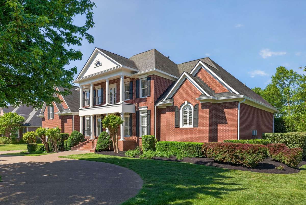 A side view of the well-trimmed hedges and well-shaded circular driveway