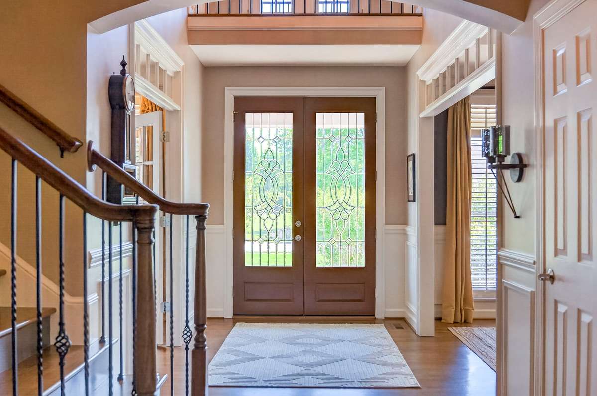A charming view of the foyer highlights the glass-paned double doors, wrought-iron spindles, and elegant molding.