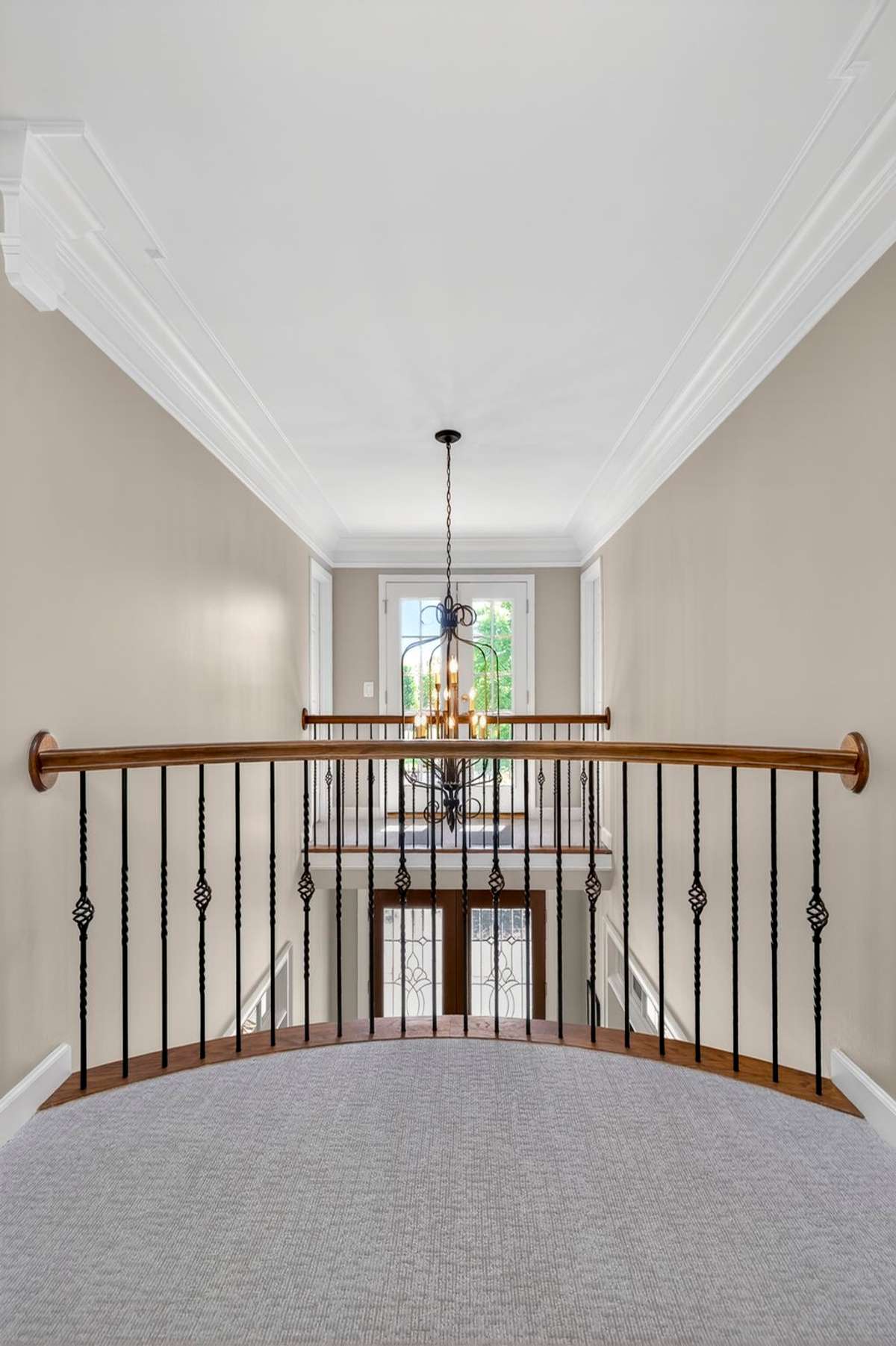 A curved railing overlooks the foyer and front balcony.
