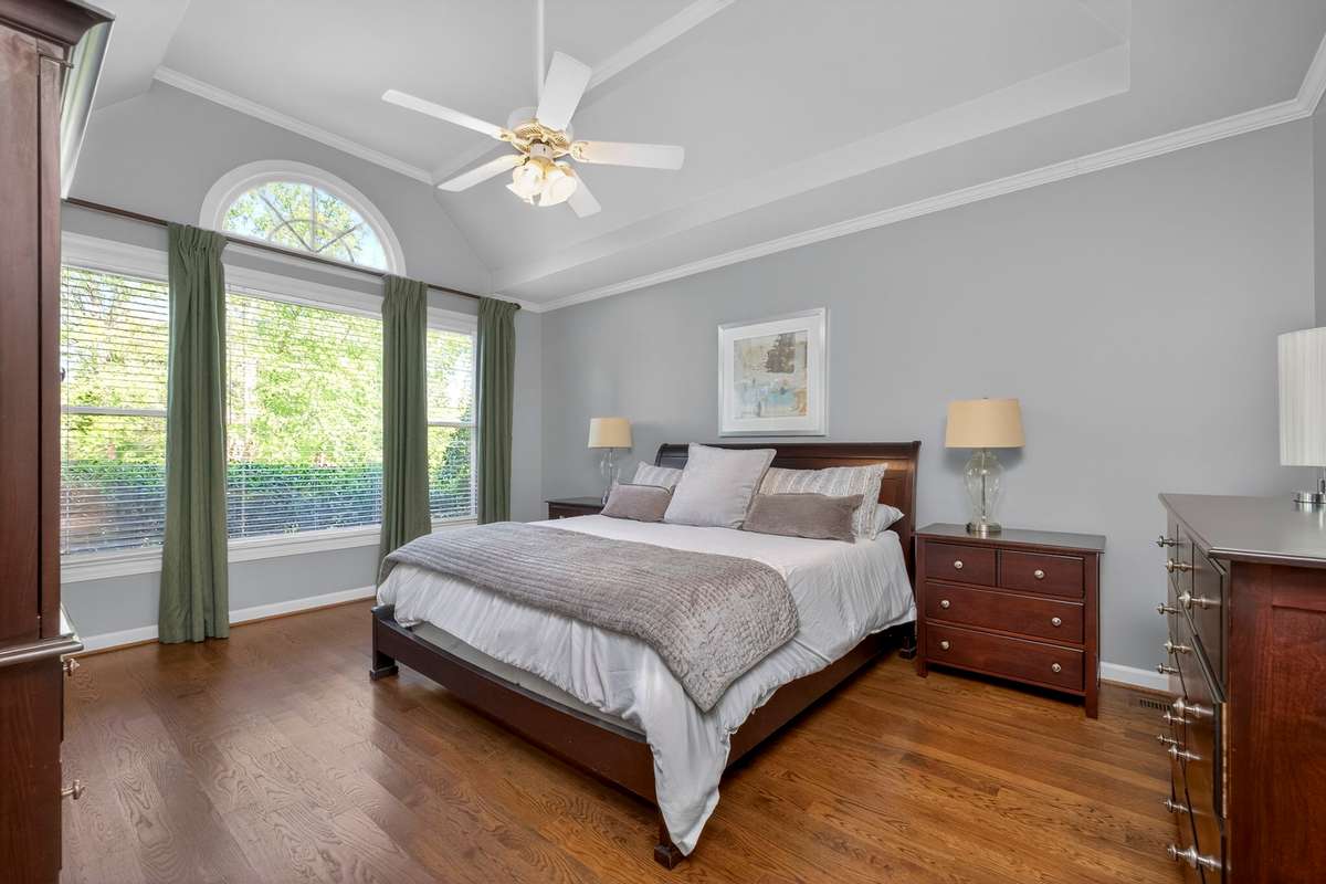 The oversized primary suite is flooded with natural light and features vaulted tray ceilings and elegant sand-and-finish hardwood floors.