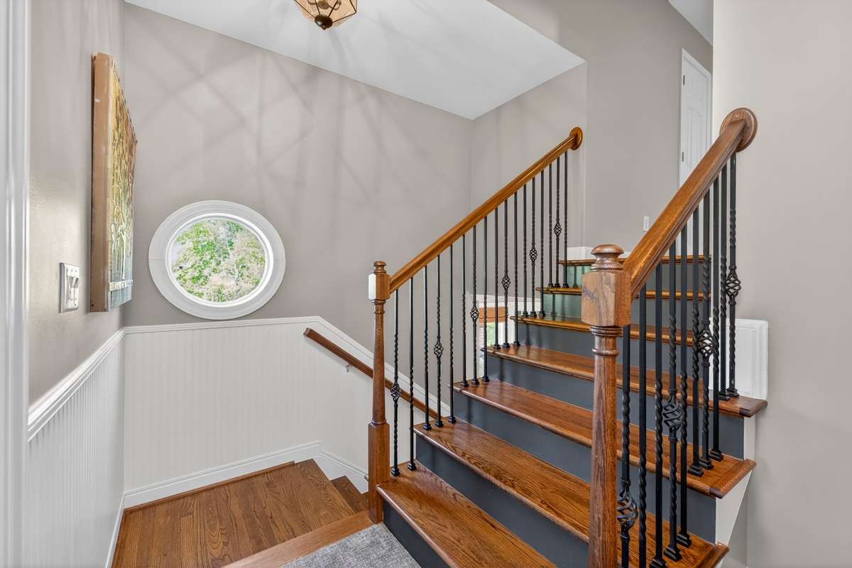 The stairwell landing features a charming circular window and beadboard chair rail.