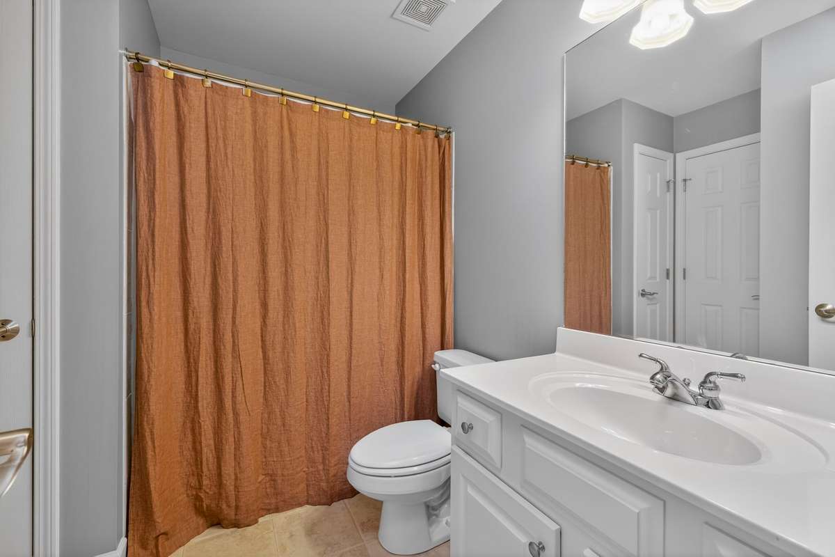 Bedroom four boasts its own full bathroom, with a large vanity, fresh paint, and tiled shower.