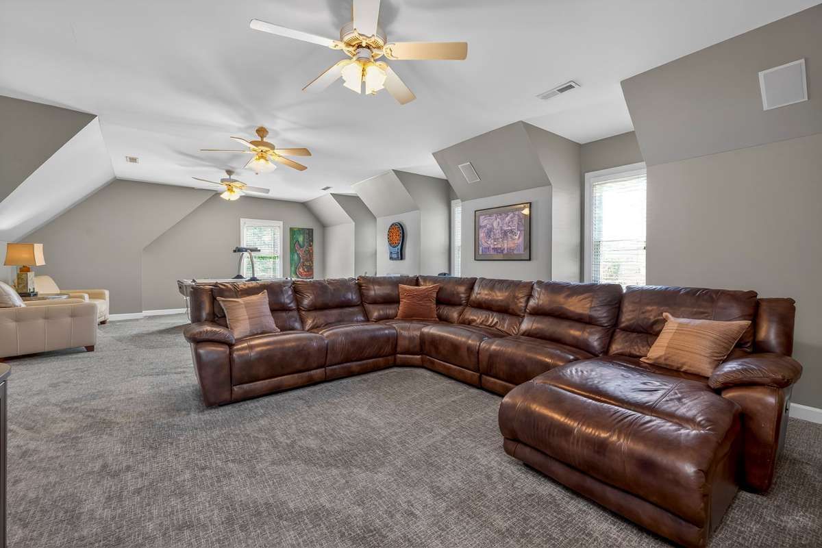 Spacious bonus room with vaulted ceilings, multiple ceiling fans, and flexible layout—perfect for a media room, game space, or home gym.