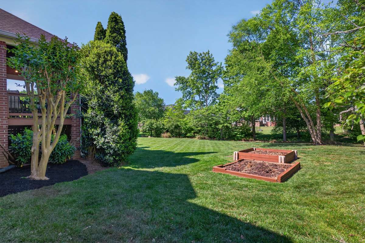 The well-cared for backyard features a level lot, plenty of shade, an invisible fence, irrigation system, and raised beds.