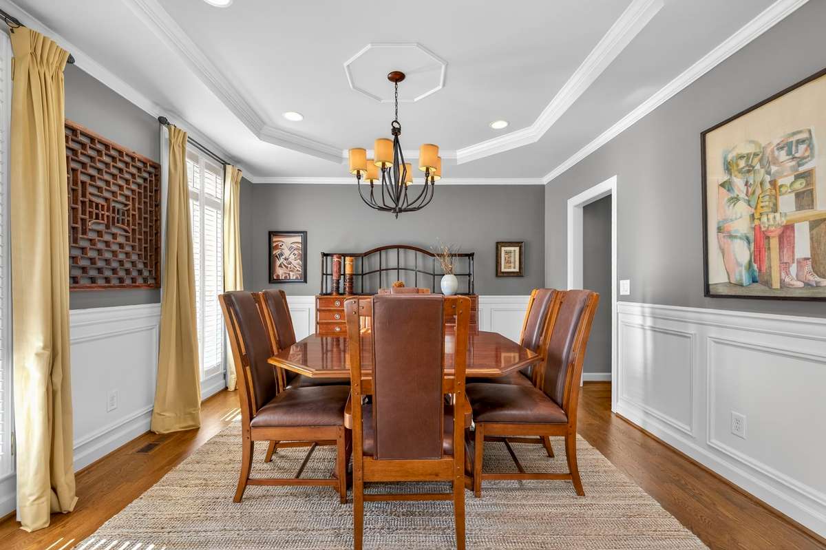 The spacious dining room features a tray ceiling, crown molding, and picture-frame chair rail, with sand-and-finish hardwoods that grant warmth to the space.
