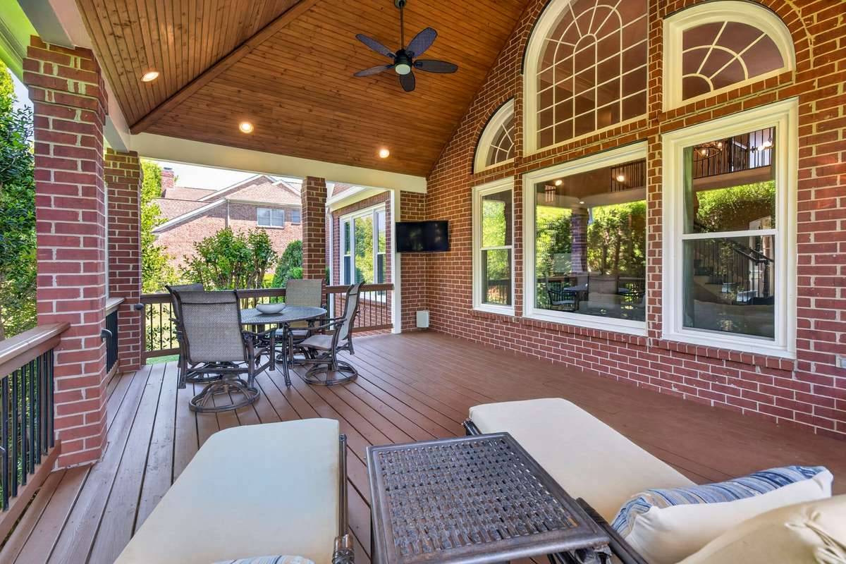 The living room allows a charming view of the covered deck, which is accentuated by a tongue-and-groove ceiling, brick columns, recessed lighting, and ceiling fans for those warm summer days.