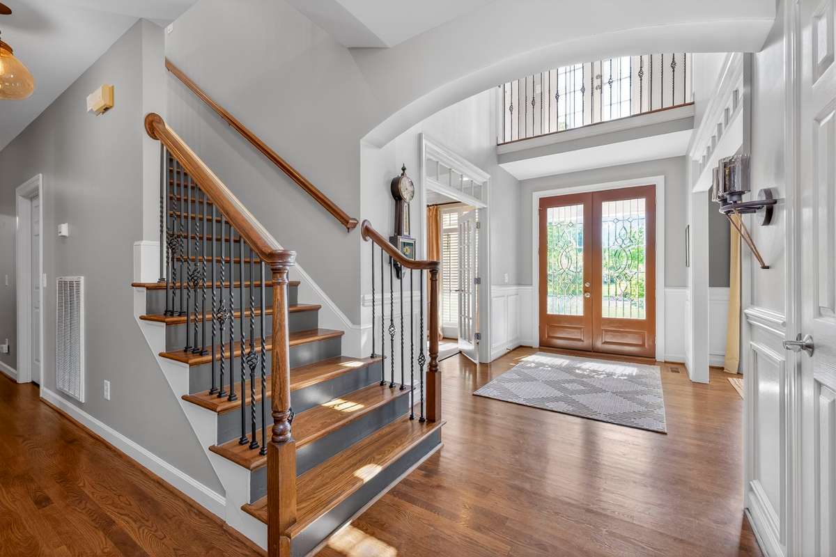 A view of the foyer and stairwell from the inside - the warmth of the sand-and-finish hardwood floors and abundant natural light create an incomparable first impression.
