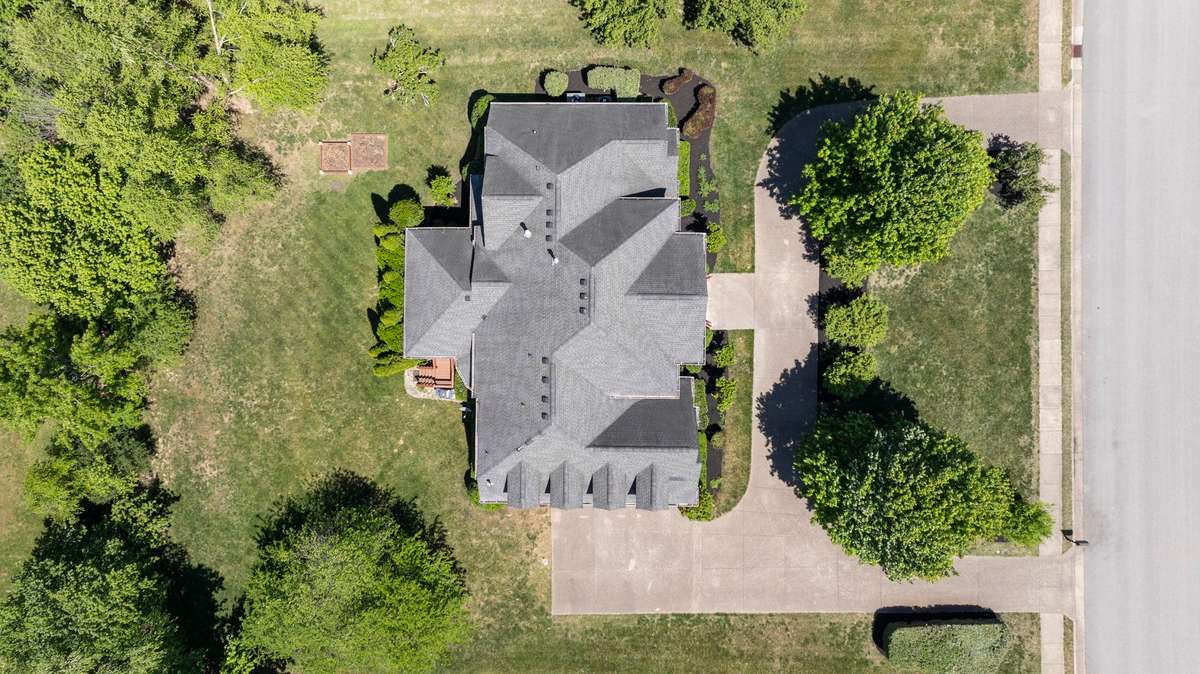 An aerial view showcases the circular drive, private backyard, and generous square footage.