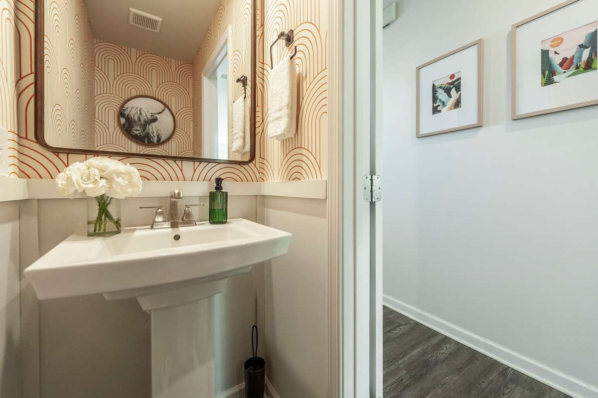 Charming powder room featuring custom wallpaper that adds personality and a stylish, upscale touch.