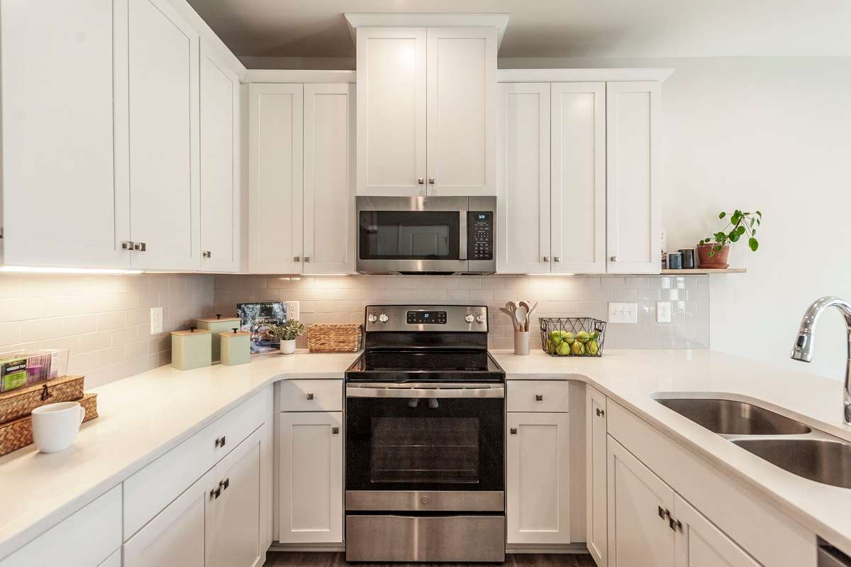 Tile backsplash adds texture and visual interest while complementing the bright white cabinets and granite surfaces.